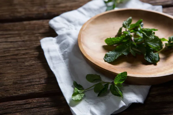 Hojas de menta fresca en plato de madera —  Fotos de Stock