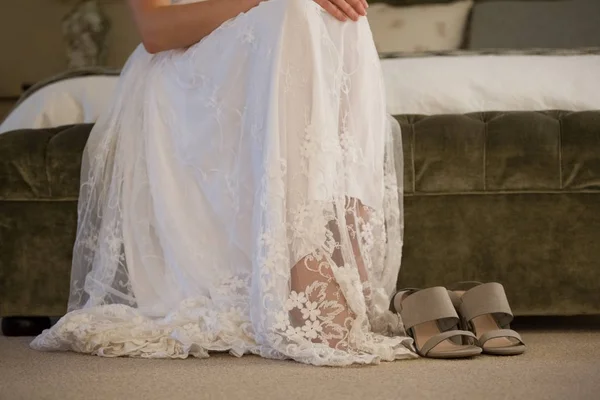 Невеста сидит в сандалиях на кровати — стоковое фото