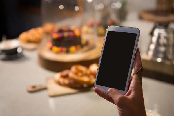 Vrouw met behulp van mobiele telefoon in restaurant — Stockfoto