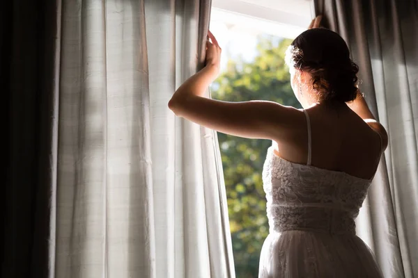 Braut im Brautkleid schaut durchs Fenster — Stockfoto