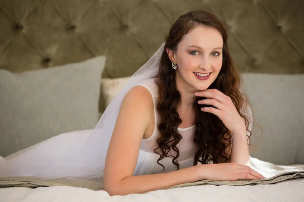 Bride in wedding dress lying on bed — Stock Photo, Image