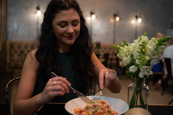 Belle femme ayant de la nourriture à table — Photo