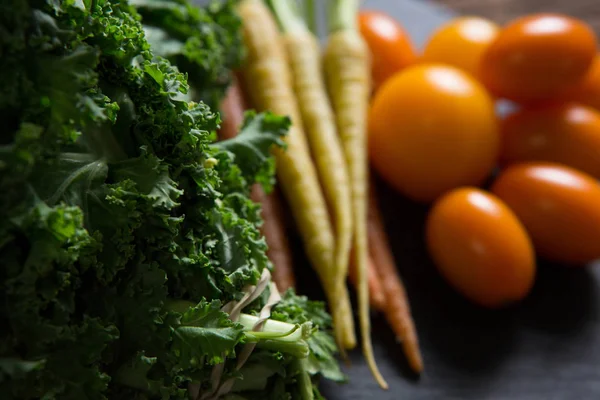 Горчичная зелень, морковь и помидоры на подносе — стоковое фото