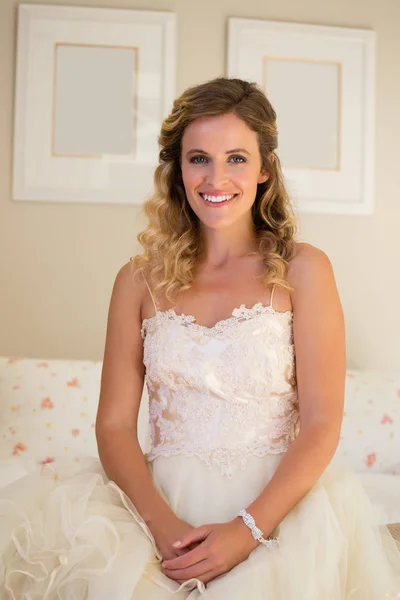 Mariée en robe de mariée assise sur le lit — Photo