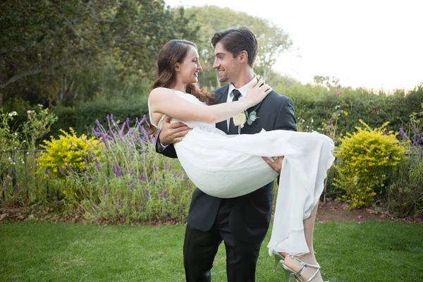 Bridegroom carrying bride while walking — Stock Photo, Image