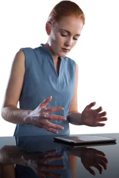 Empresária gesticulando sobre tablet à mesa — Fotografia de Stock