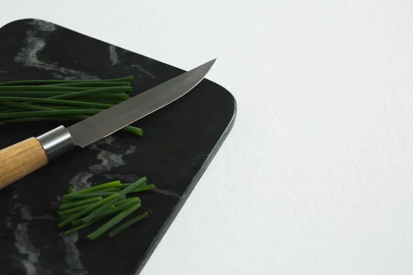 Scallions and knife on black slate plate — Stock Photo, Image