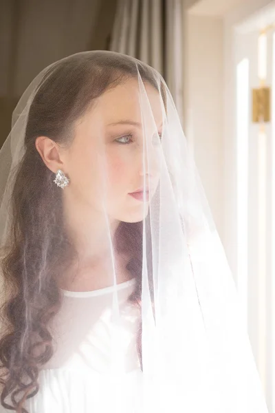 Beautiful bride standing by window — Stock Photo, Image