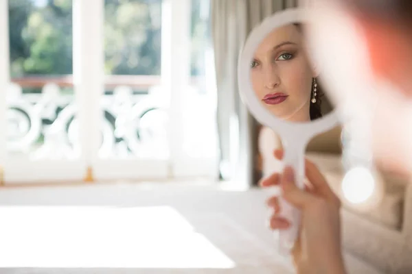 Невеста смотрит в ручное зеркало дома — стоковое фото