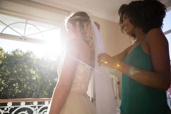 Косметик настраивает вуаль на волосы невесты — стоковое фото