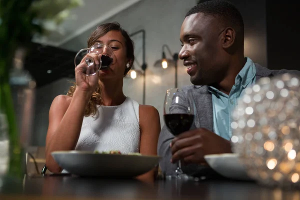 Casal tendo vinho tinto enquanto janta — Fotografia de Stock
