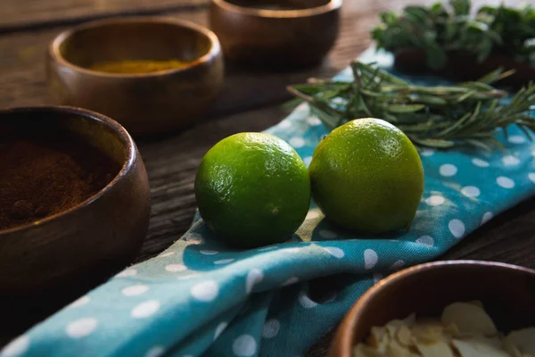 Lime frukt med örter på träbord — Stockfoto