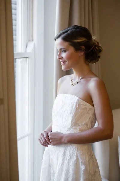 Bride looking through window at home — Stock Photo, Image