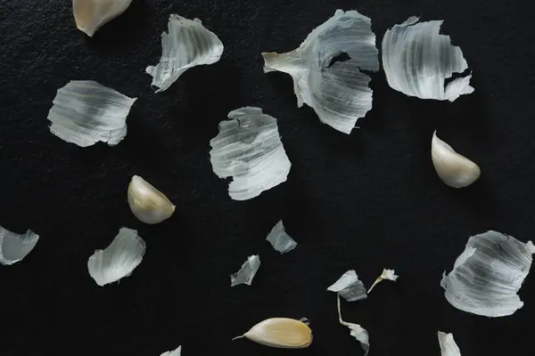 Garlics and peeled on black background — Stock Photo, Image
