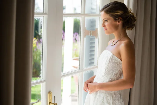 Noiva olhando através da janela em casa — Fotografia de Stock
