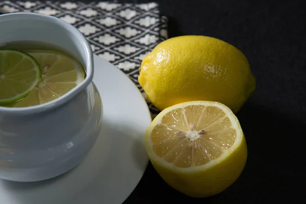 Чашка чая с лимоном на черном фоне — стоковое фото
