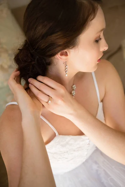 Bride adjusting hair while siting on sofa — Stock Photo, Image