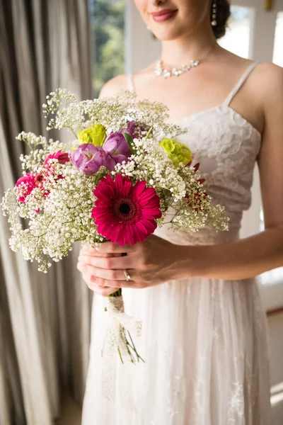 Невеста в свадебном платье с букетом дома — стоковое фото