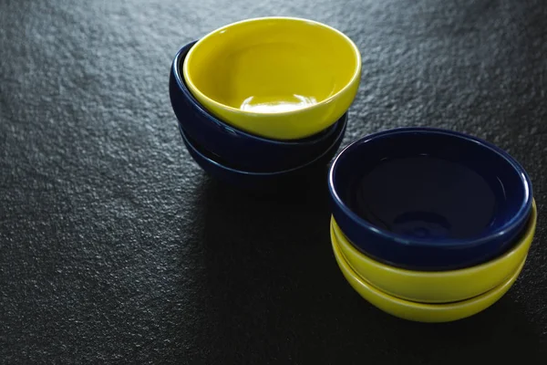 Желтый и синий пластиковые миски на черном фоне — стоковое фото