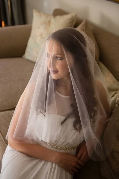 Bride in wedding dress sitting on sofa — Stock Photo, Image