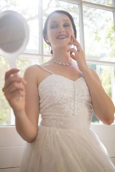 Attractive bride looking into hand mirror — Stock Photo, Image