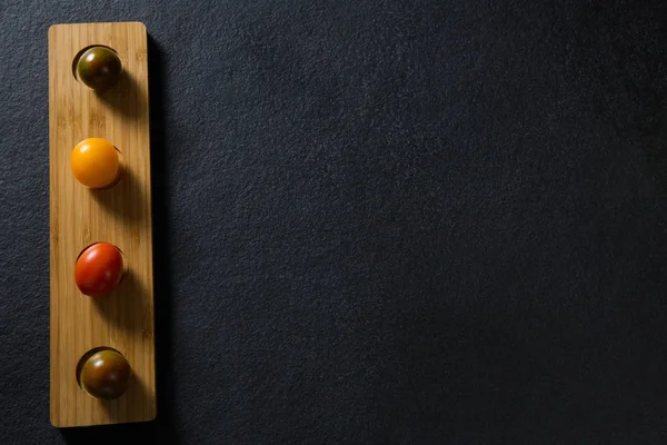 Различные помидоры расположены в деревянном подносе — стоковое фото
