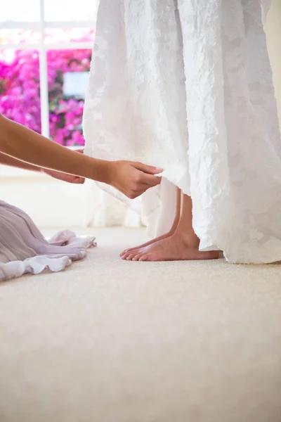 Подружка невесты регулирует платье невесты в примерочной — стоковое фото