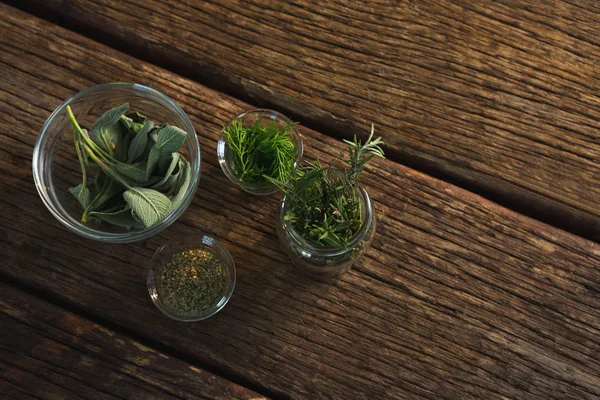 Různé bylinky ve sklenici na dřevěný stůl — Stock fotografie