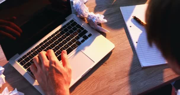 Executive writing on paper while using laptop at his desk — Stock Video