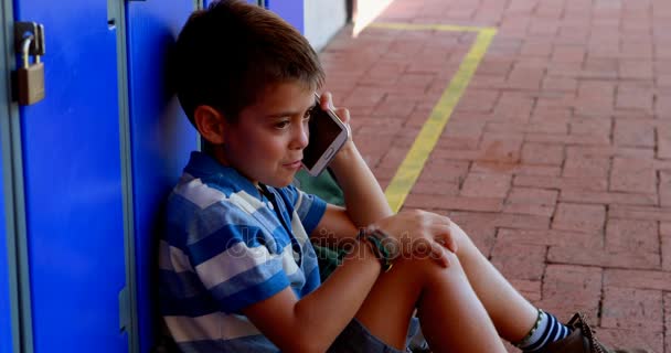Школьник разговаривает по мобильному телефону в раздевалке — стоковое видео