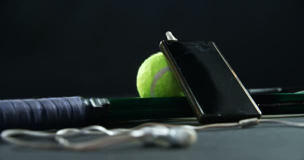 Pelotas de tenis, raqueta y teléfono móvil con auriculares — Vídeo de stock