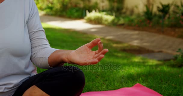 Senior kvinna utför yoga i trädgården — Stockvideo