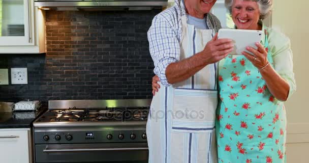 Senior couple using digital tablet in kitchen — Stock Video