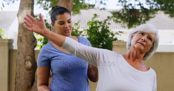 Entrenador que ayuda a la mujer mayor en el ejercicio — Vídeos de Stock