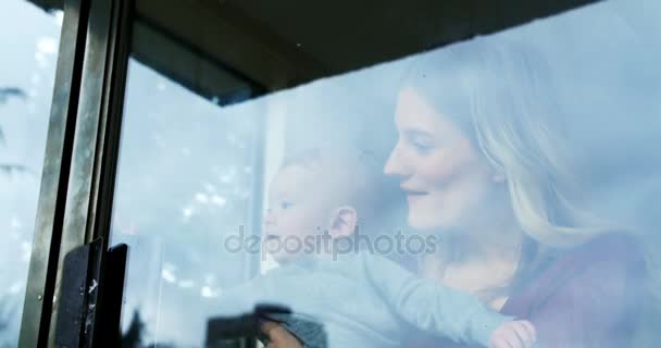 Мать с ребенком стоит у окна — стоковое видео