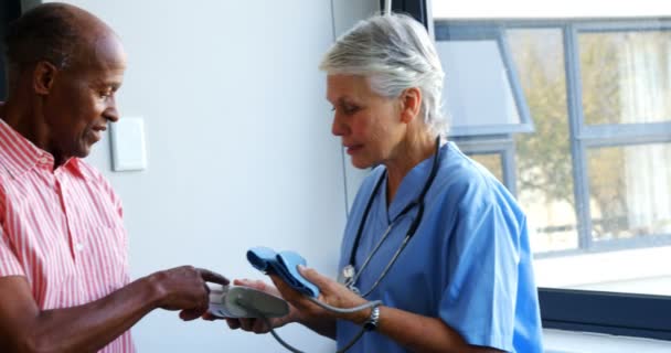 Médico explicando sobre o monitor de pressão arterial para homem idoso — Vídeo de Stock