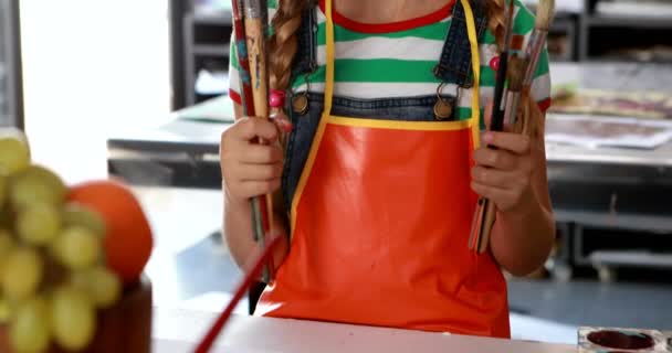 Schoolmeisje staande met schilderskwast — Stockvideo