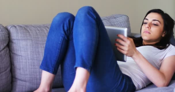 Mujer usando tableta digital mientras se relaja en el sofá — Vídeo de stock