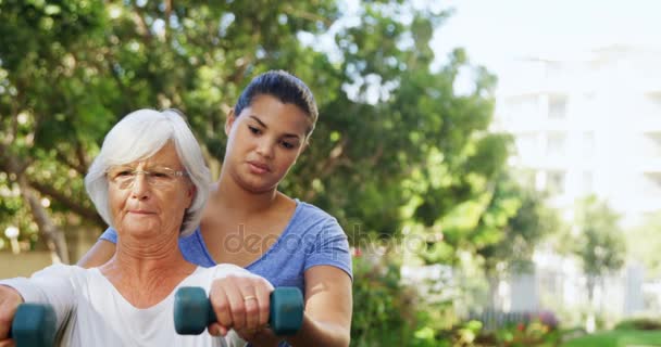 Entrenador que ayuda a la mujer mayor en el ejercicio — Vídeo de stock