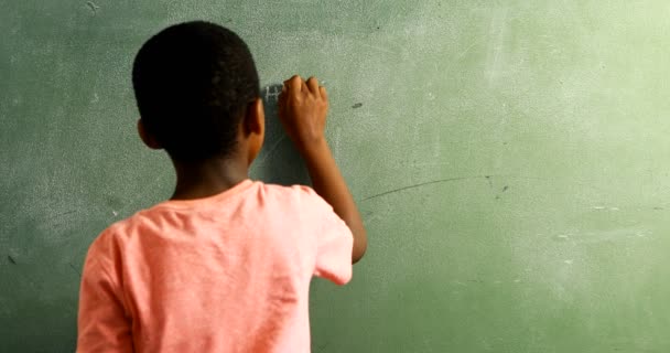 Schoolboy doing mathematics on chalkboard in classroom — Stock Video