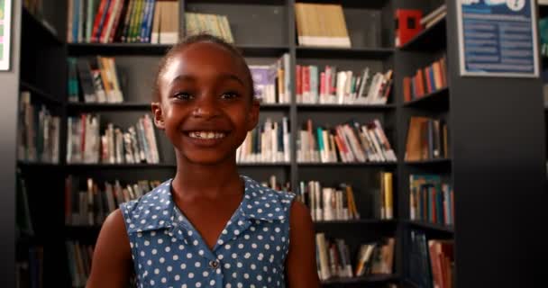 Heureuse écolière debout dans la bibliothèque — Video