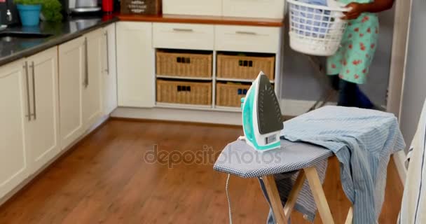 Hombre sosteniendo cubo lleno de ropa en la cocina — Vídeos de Stock