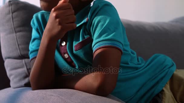 Ledsen pojke sitter på soffan i vardagsrummet — Stockvideo