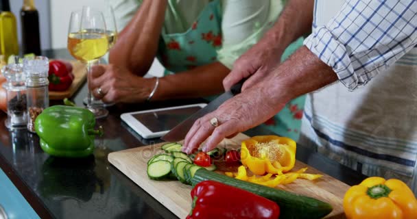 Pareja mayor cortando verduras en la cocina — Vídeo de stock