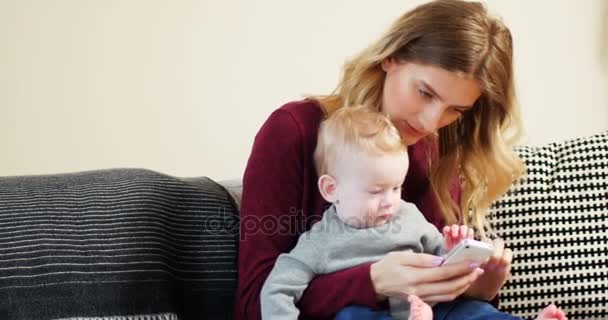 Anne ve bebek kanepede istimal hareket eden telefon — Stok video