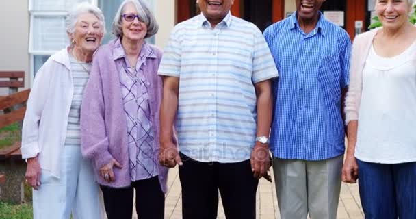 Щасливі старші друзі, що стоять разом на газоні — стокове відео