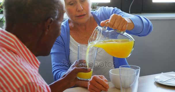 Senior woman pouring juice into glass to her friend — Stock Video
