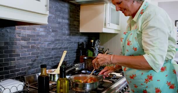 Senior vrouw koken voedsel in keuken — Stockvideo