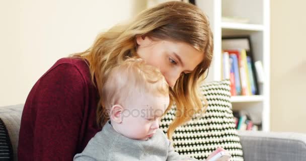 Mutter und Baby mit Handy auf dem Sofa — Stockvideo