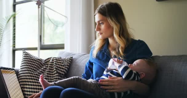 母彼女の赤ちゃんを供給しながらノート パソコンを使用して — ストック動画